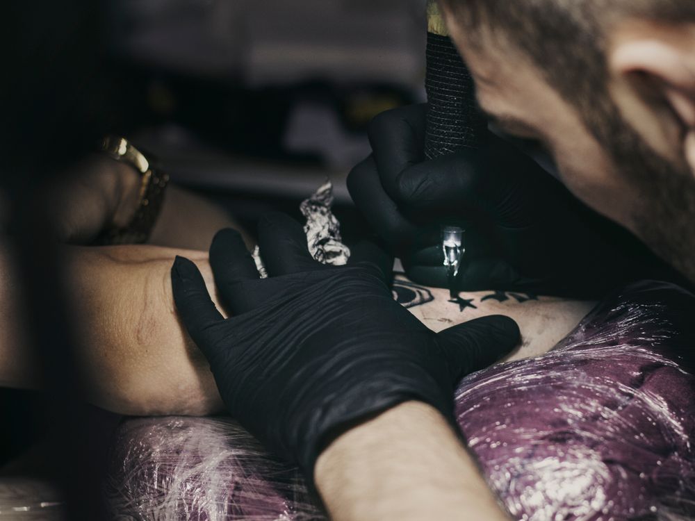 Artista tatuando el brazo de un cliente